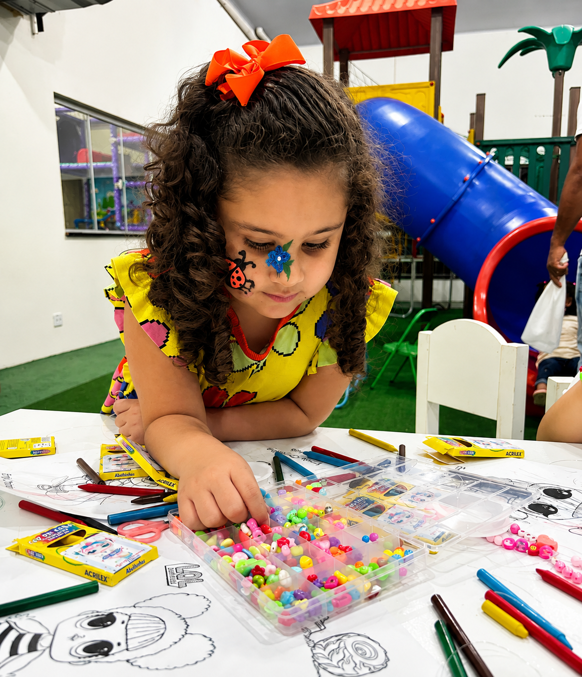 Menina montando pulseira na oficina de missangas