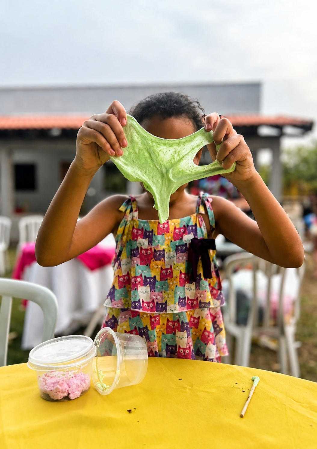 Menina esticando slime verde na oficina
