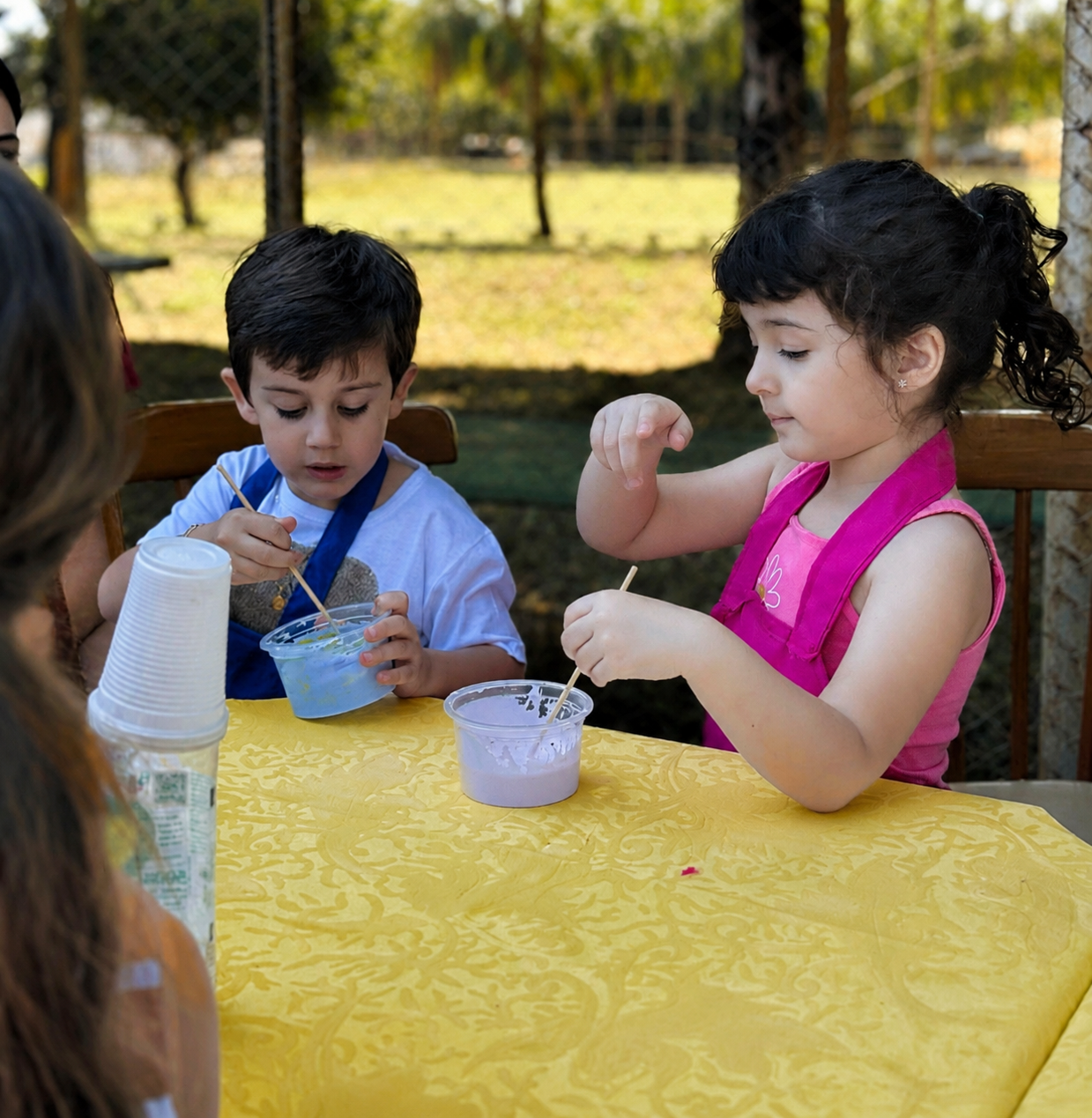 Crianças fazendo slime com aventais na mesa